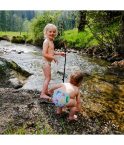 Kinderen met zwemluiers van popolini spelen in beek.