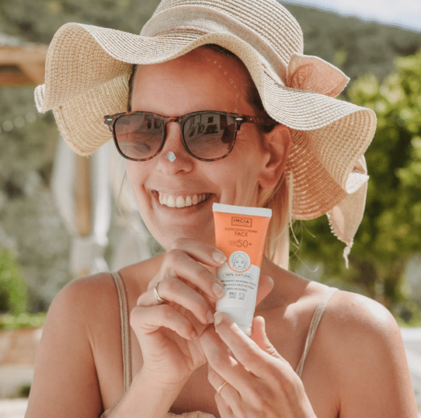 Vrouw met incia zonnebrandcreme voor gezicht.