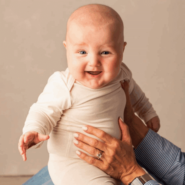 Baby met ecrukleurige romper met lange mouw.