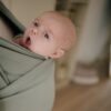 Baby in rekbare groene draagdoek.