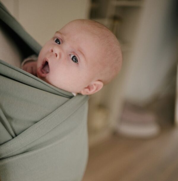 Baby in rekbare groene draagdoek.