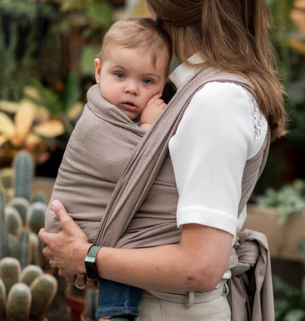 Baby in geweven draagdoek van biologisch katoen in kleur bruin.